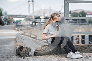 child in protective mask using laptop on street air