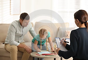 Child psychotherapist working with little girl and father in office