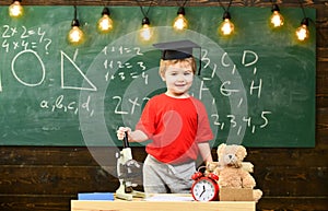 Child, pupil on smiling face near microscope. First former interested in studying, education. Wunderkind concept. Kid