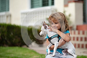Child with puppies hugging. Funny child playing with dog outdoor.