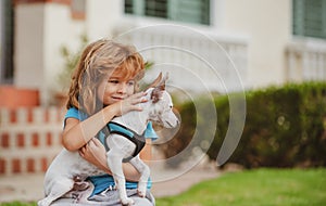 Child with puppies hugging. Funny child playing with dog outdoor.