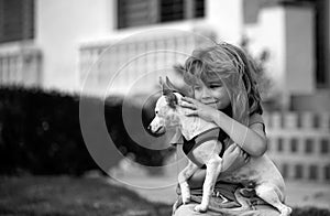 Child with puppies hugging. Funny child playing with dog outdoor.