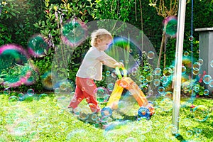 Child Pushing Toy in Sunny Backyard with Soap Bubbles