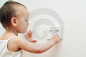 Child put finger in socket. Baby touching the power socket