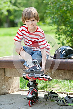 The child put on roller skates on a bench