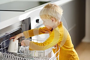 Child puts dirty crockery in the home dishwasher. Close-up