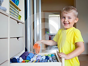 The child puts his clothes on. The boy pulls the T-shirt out of