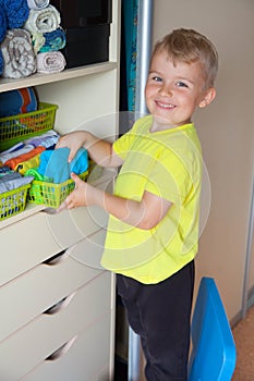 The child puts his clothes on. The boy pulls the T-shirt out of