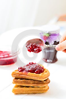 Child puts a jam of jam, jam on Viennese waffles. Morning, breakfast