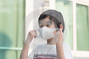 Child puts a safety mask on his face by himself