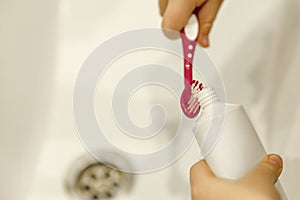 A child puts toothpaste on a brush in the bathroom. Dental care and hygiene from childhood. Close-up