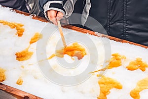 Child putting maple taffy on a wooden stick photo