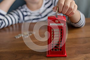 child putting money to the coin box look like traditional british call box, saving money concept