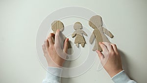 Child putting paper family and heart on white background, orphan needs home