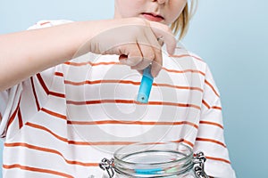 Child is putting used batteries in a jar for recycling.