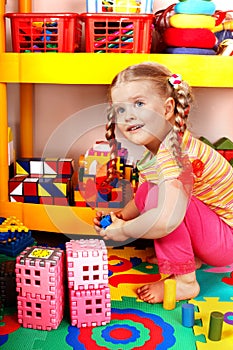 Child with puzzle and block in play room.