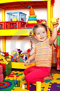 Child with puzzle and wood block in play room.