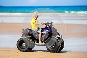 Child on quad bike at beach. All-terrain vehicle.