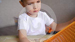 A child is quarantined at home and plays in the sandbox during the pandemic and Covid-19. Boy makes sand molds