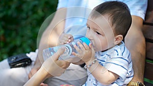 Child quenches thirst with water from a bottle.