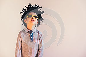 Child with rastafari wig dancing cheerful, isolated copy space white background photo