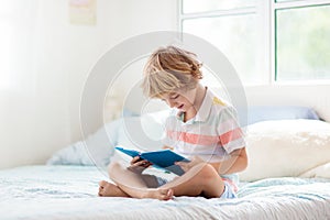 Child reading in bed. Kids read. Boy at home
