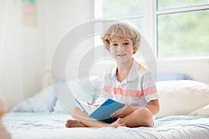 Child reading in bed. Kids read. Boy at home