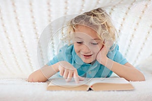 Child reading book in bed. Kids read books