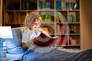 Child reading book in bed. Kids read at night