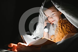 Child reading book in bed. Kids read at night. Little boy with fairy tale books in bedroom . Education for young