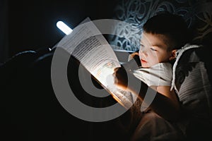 Child reading book in bed. Kids read at night. Little boy with fairy tale books in bedroom . Education for young