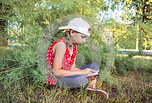 Child reading book or bible outdoors . Cute little girl reading the Bible .