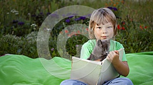 Child reading book with Cat in the yard, Boy with kitten pet reading magazine on the grass in the park