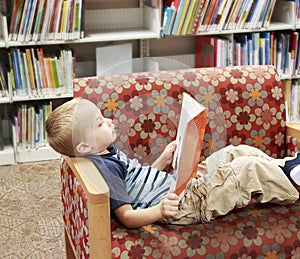 Child reading a book on a couch at the library