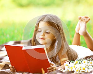 Child reading a book on the grass