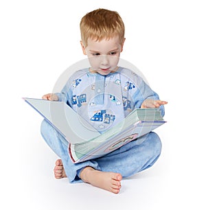 Child Reading Book. Kin Sitting in Blue Nightwear and Reading, White Isolated photo