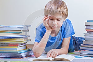 Child reading book between the stacks of books.