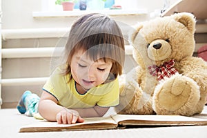 Child reading book for toy teddy bear, little girl learning and