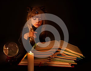 Child reading magic book at candle.