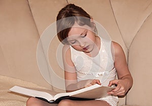 A child reads a thick encyclopedia. The baby is reading a book in close-up