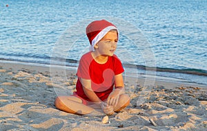 A child in a red Christmas hat playing on the sea.