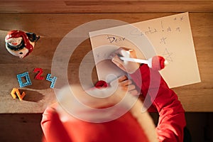 child in a red hat dreams of gifts and writes a letter to Santa