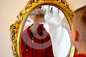 The child reflected in a distorting mirror. A fun reflection of the boy. Children`s entertainment