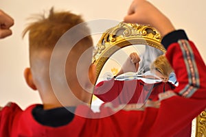 The child reflected in a distorting mirror. A fun reflection of the boy. Children`s entertainment