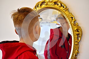 The child reflected in a distorting mirror. A fun reflection of the boy. Children`s entertainment