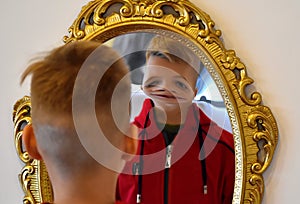 The child reflected in a distorting mirror. A fun reflection of the boy. Children`s entertainment