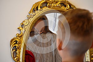 The child reflected in a distorting mirror. A fun reflection of the boy. Children`s entertainment