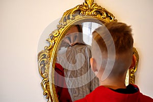 The child reflected in a distorting mirror. A fun reflection of the boy. Children`s entertainment