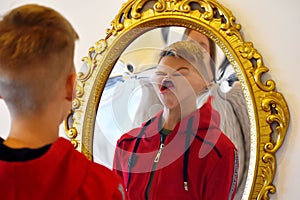 The child reflected in a distorting mirror. A fun reflection of the boy. Children`s entertainment photo