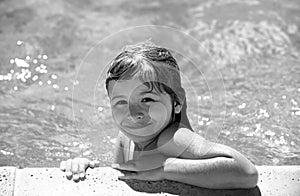 Child relax in summer swimming pool. Little boy playing in outdoor swimming pool in water on summer vacation. Child